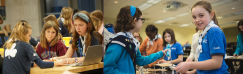 Girl guides looking at a computer and another smiling at camera