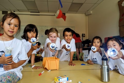 A group of campers pointing their DIY circuit flashlights towards the camera, smiling.