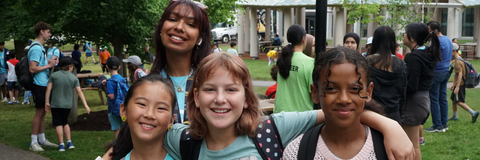 One camper leader and 3 campers smiling to the camera, outside