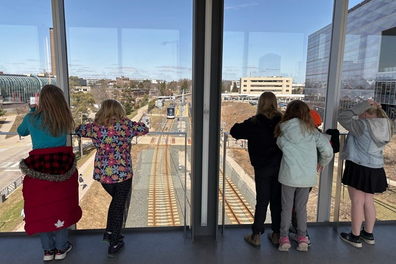 Elementary students overlooking E7 and the LRT from a bridge