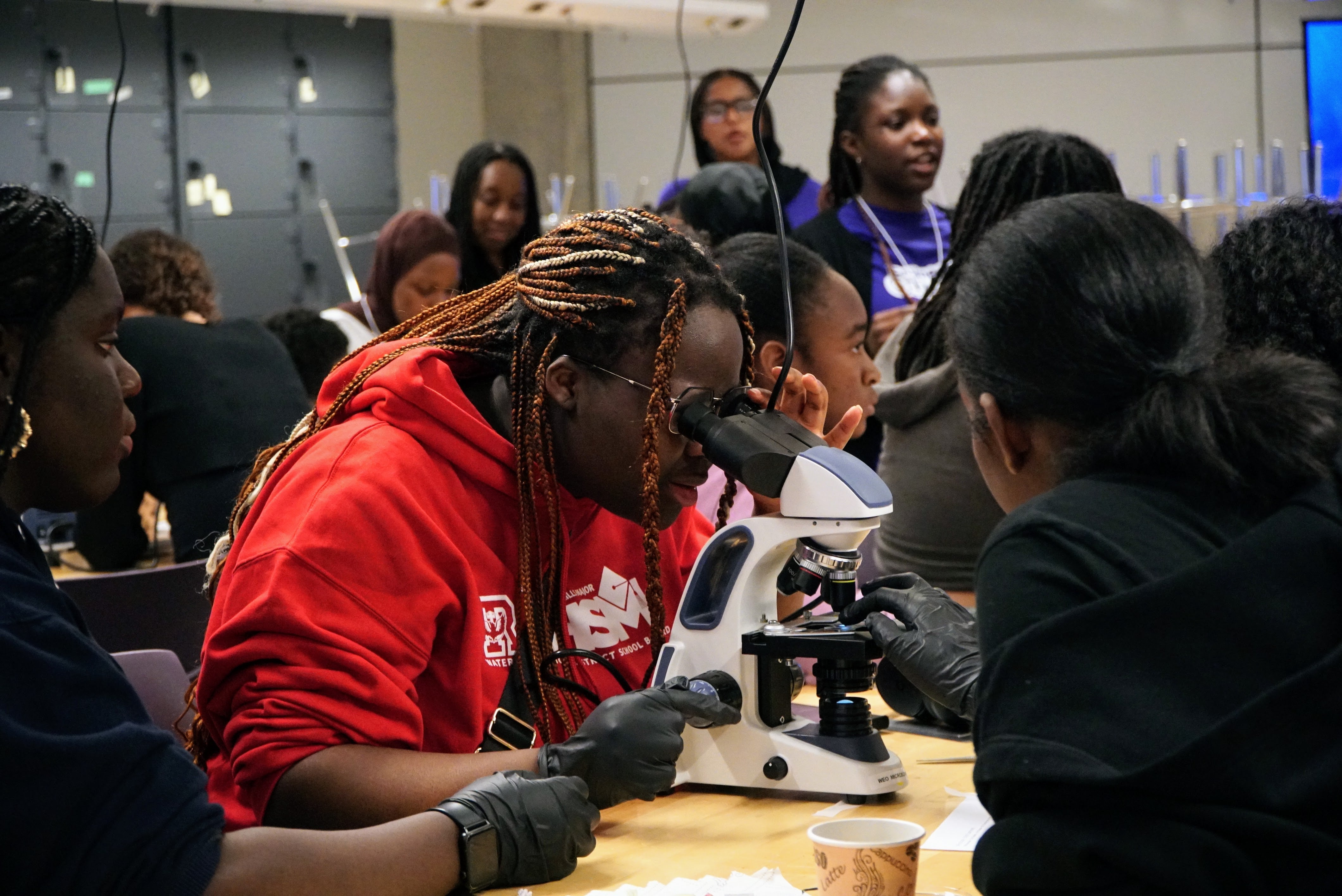 Student at STEMpowered conference looks through microscope