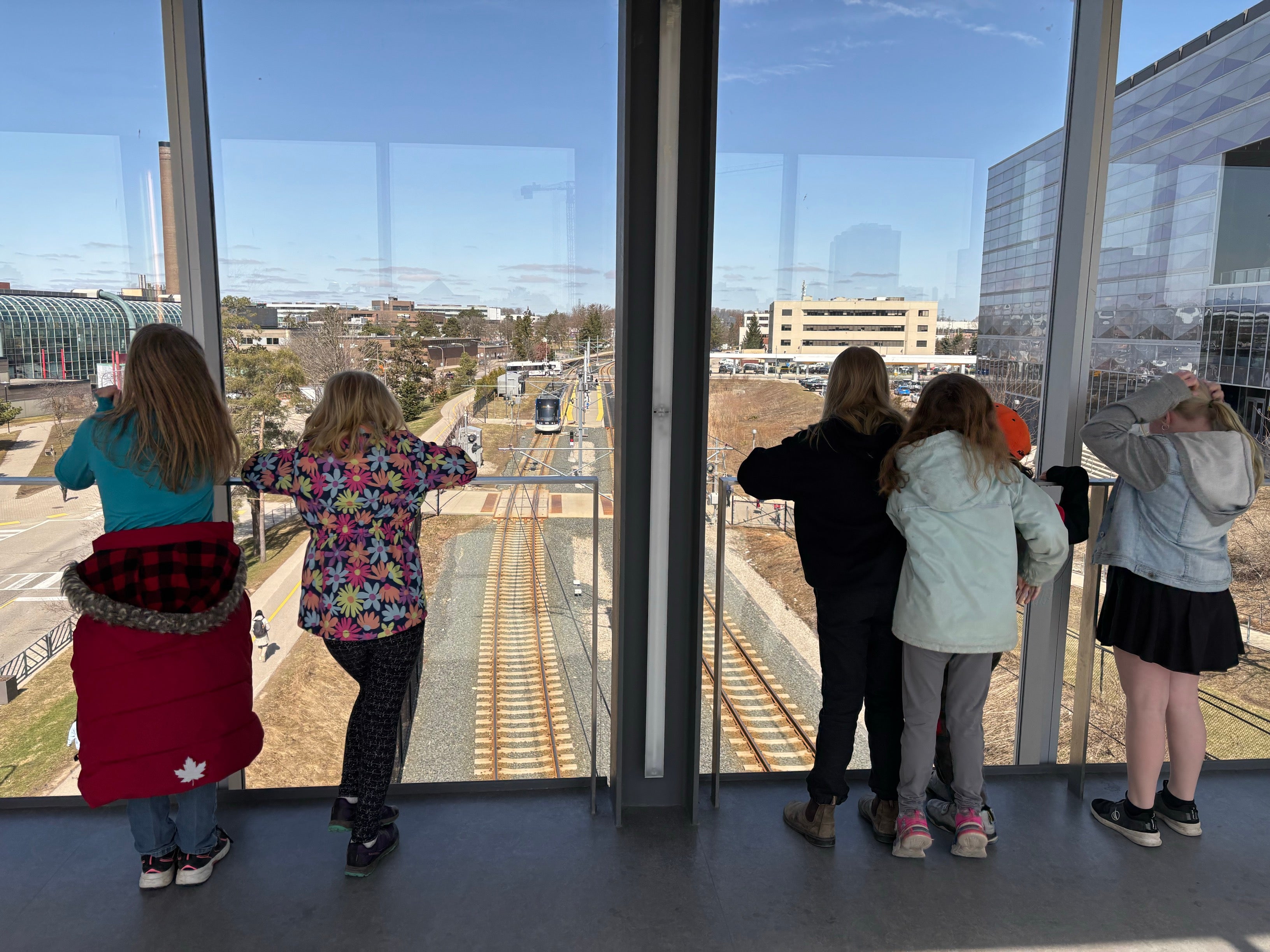 Elementary students overlooking E7 and the LRT from a bridge