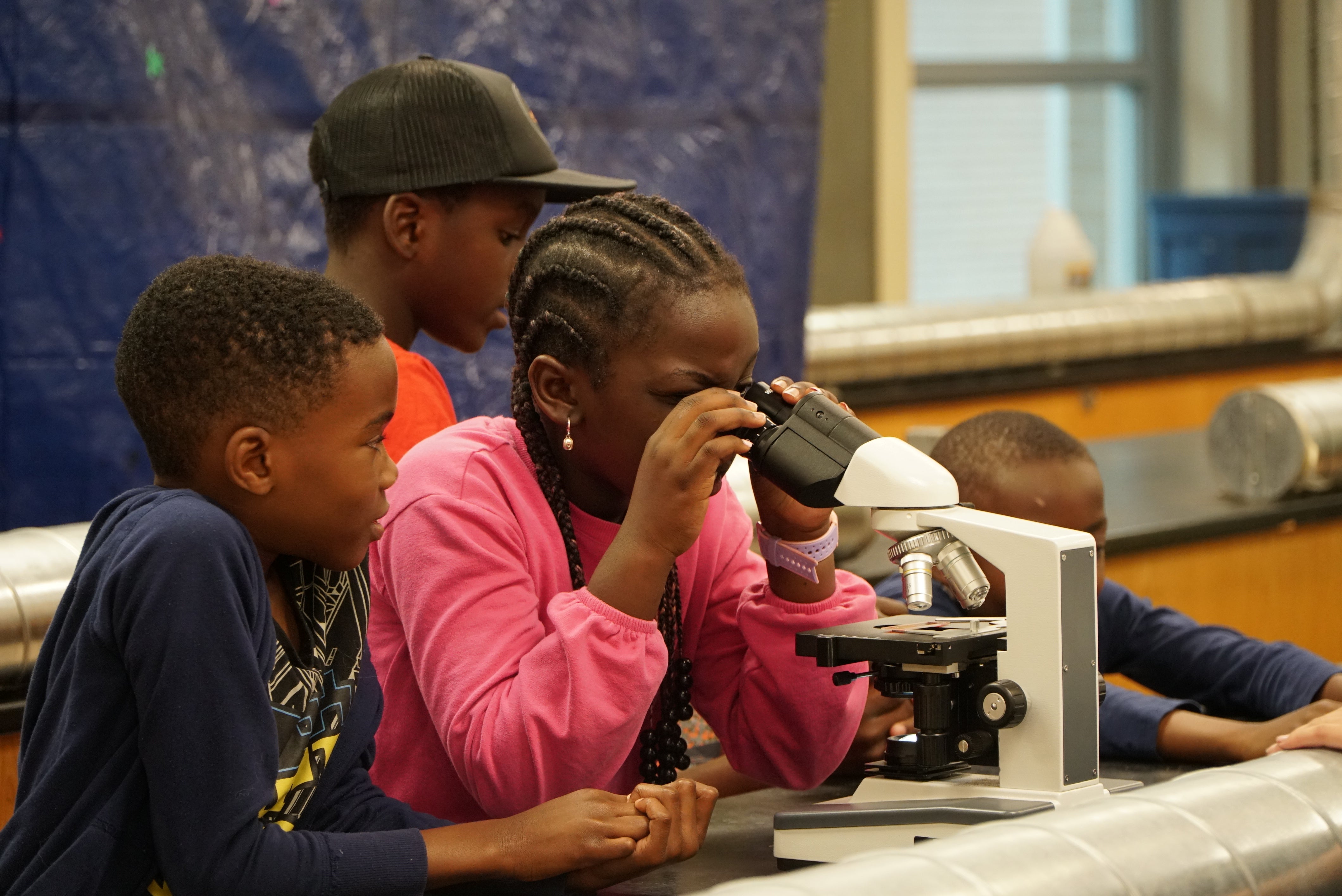 stempowered summer camper looking through microscope