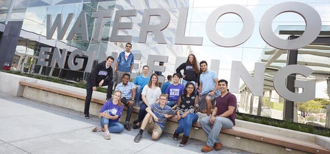 Engineering students standing in front of Waterloo Engineering sign outside of E7