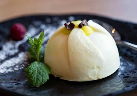 ice cream on a black plate with a sprig of mint