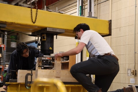 Two students working on wooden structures
