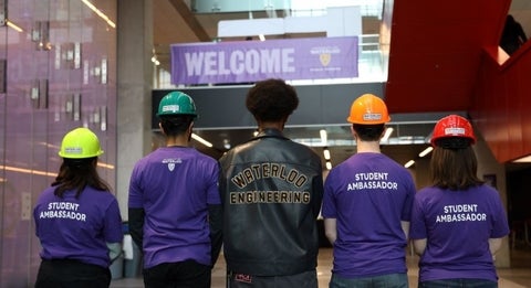 Back of student volunteer shirts with welcome sign in background