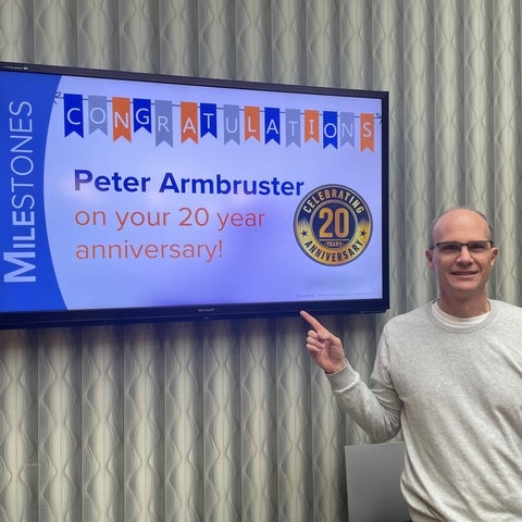 Peter pointing at the TV showing his milestone of reaching his 20 year anniversary