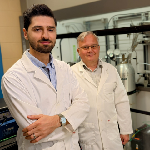 Two men pose in a lab, smiling for the camera.