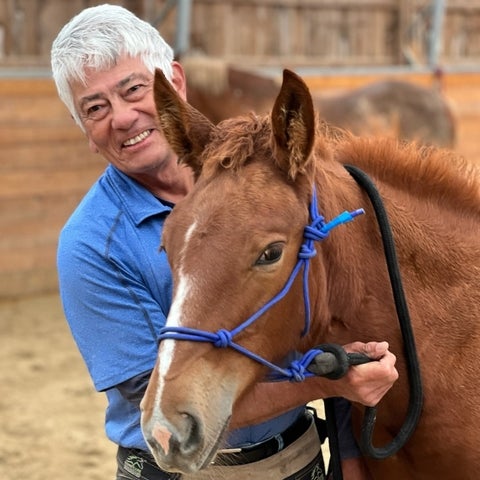 Brian wearing a blue shirt holding his horse.