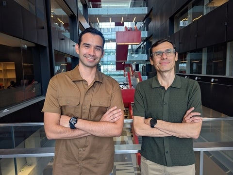 Two men stand together smiling