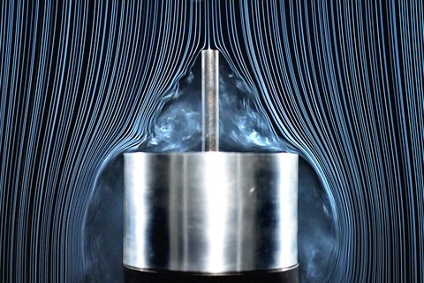 Smoke moves around two cylinders in a win tunnel.