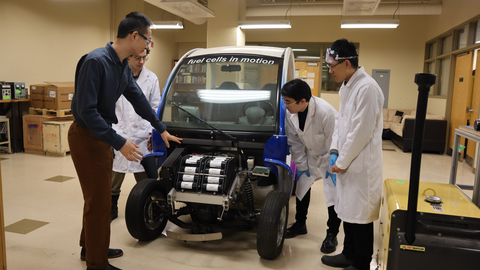 four researchers around car indoors