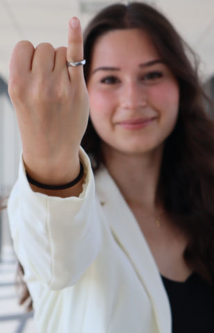 Woman holds her pinky finger up to show her Iron Ring