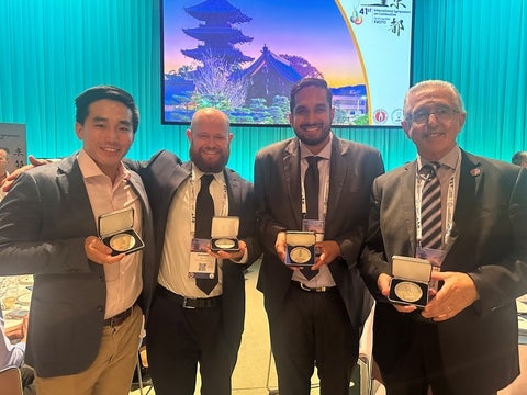 A group of four men pose with their medals. 