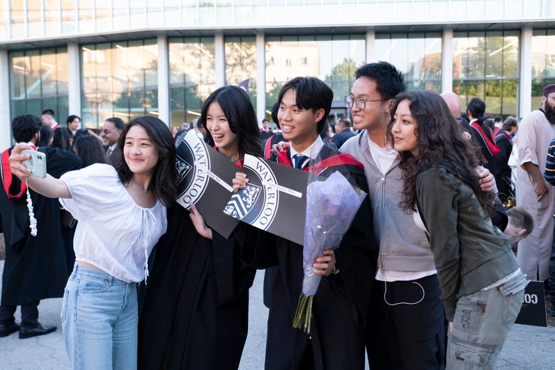 A group of new graduates take a selfie outside after convocation