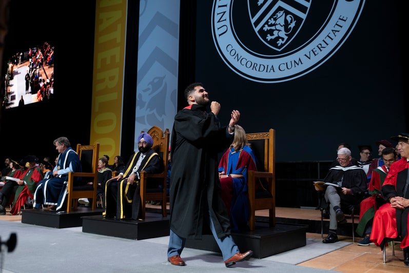 A graduate pumps his fists as he crosses the convocation stage