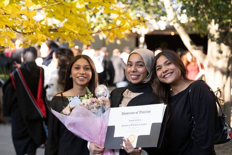 Three young woman pose outside with a Waterloo Engineering degree