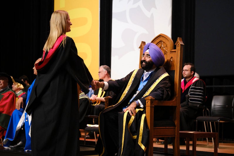 The chancellor shakes a graduate's hand on stage.