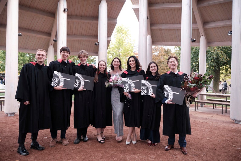 A group of graduates pose with their certificates outside 