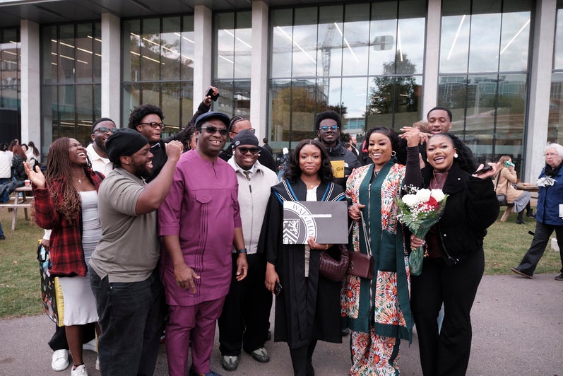 A group of young people pose with a graduate, who is holding her certificate.