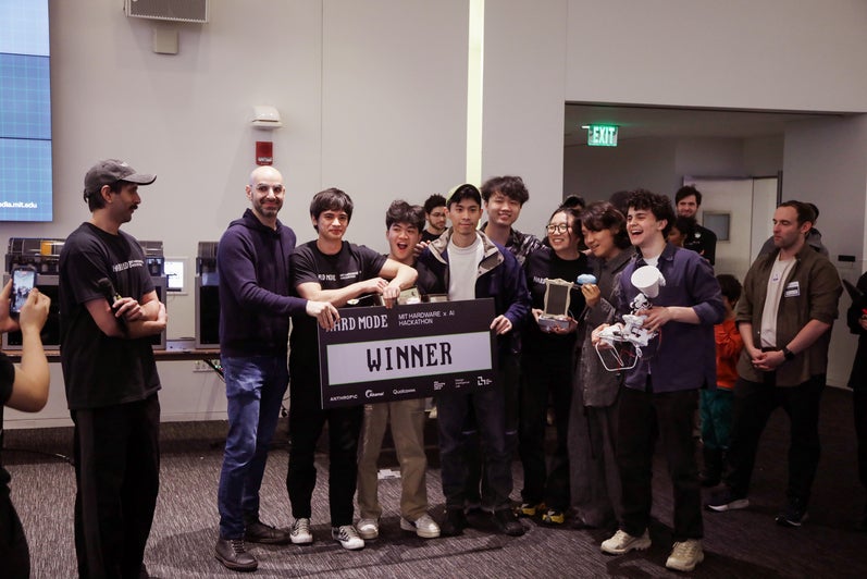 A group of students pose with a banner saying "Winner" as they accept first-prize at MIT's hackathon.