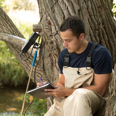Student writing in notebook outside