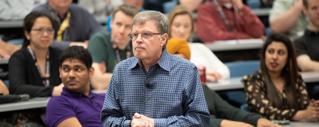 Larry Smith delivering a lecture with attendees sitting in a classroom
