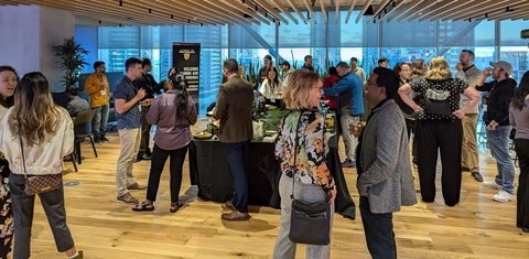 People talking in small groups in a large space overlooking the Toronto skyline