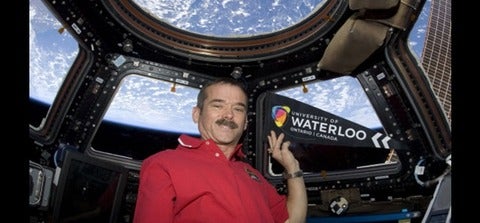 Chris Hadfield on International Space Station with UWaterloo banner