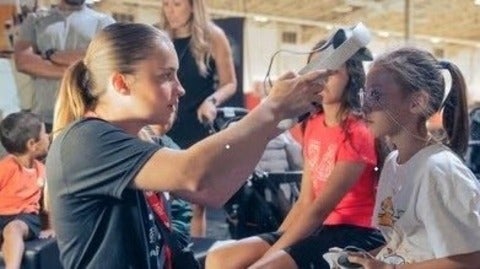 A woman puts a VR headset on a girl.