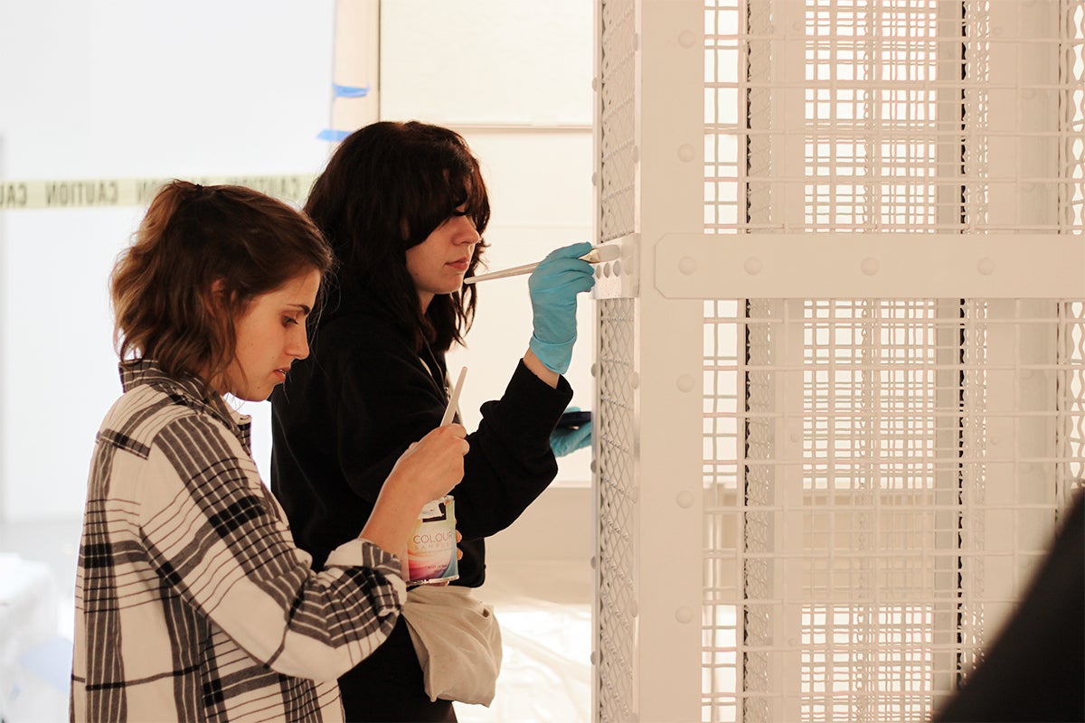 Piper Bernbaum, right, and Anna Longrigg touch up paint on the model gas column of The Evidence Room exhibit 