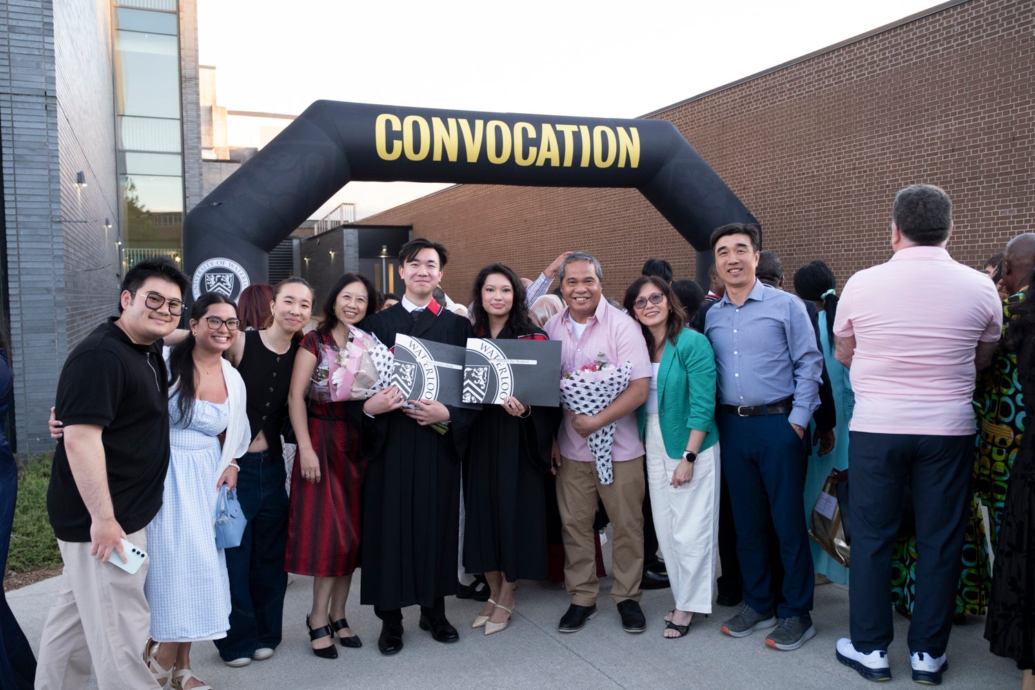 A group of new graduates and family members pose under a convocation sign