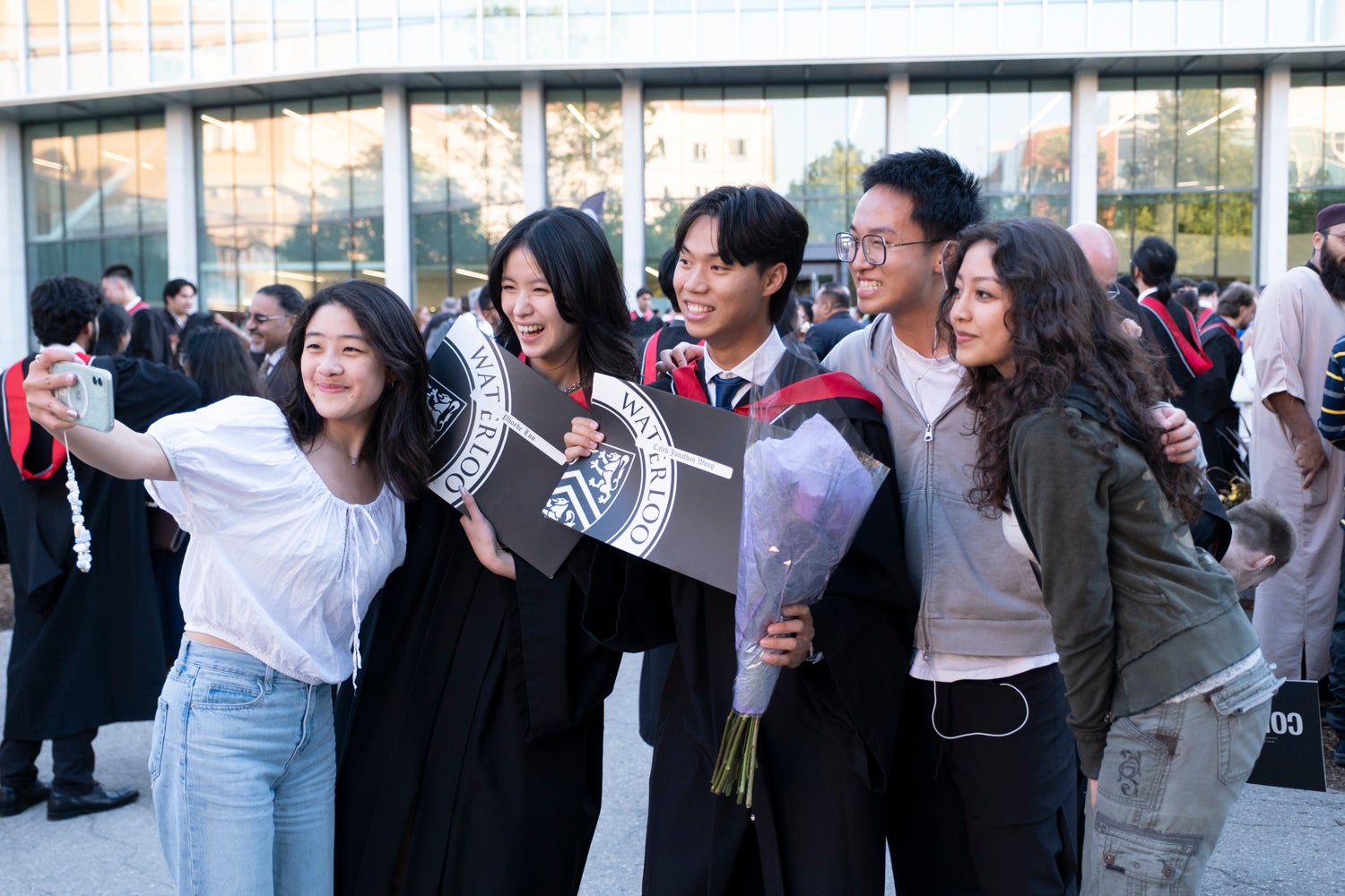 A group of new graduates take a selfie outside after convocation