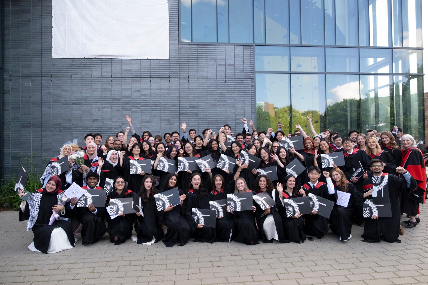 A large group of graduates pose with their degrees after convocation