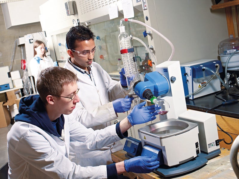 Two graduate students working in a lab with a microscope