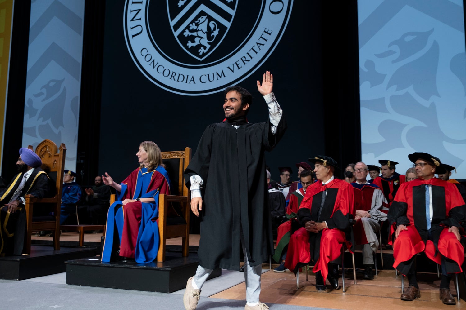 A graduate waves as he crosses the convocation stage