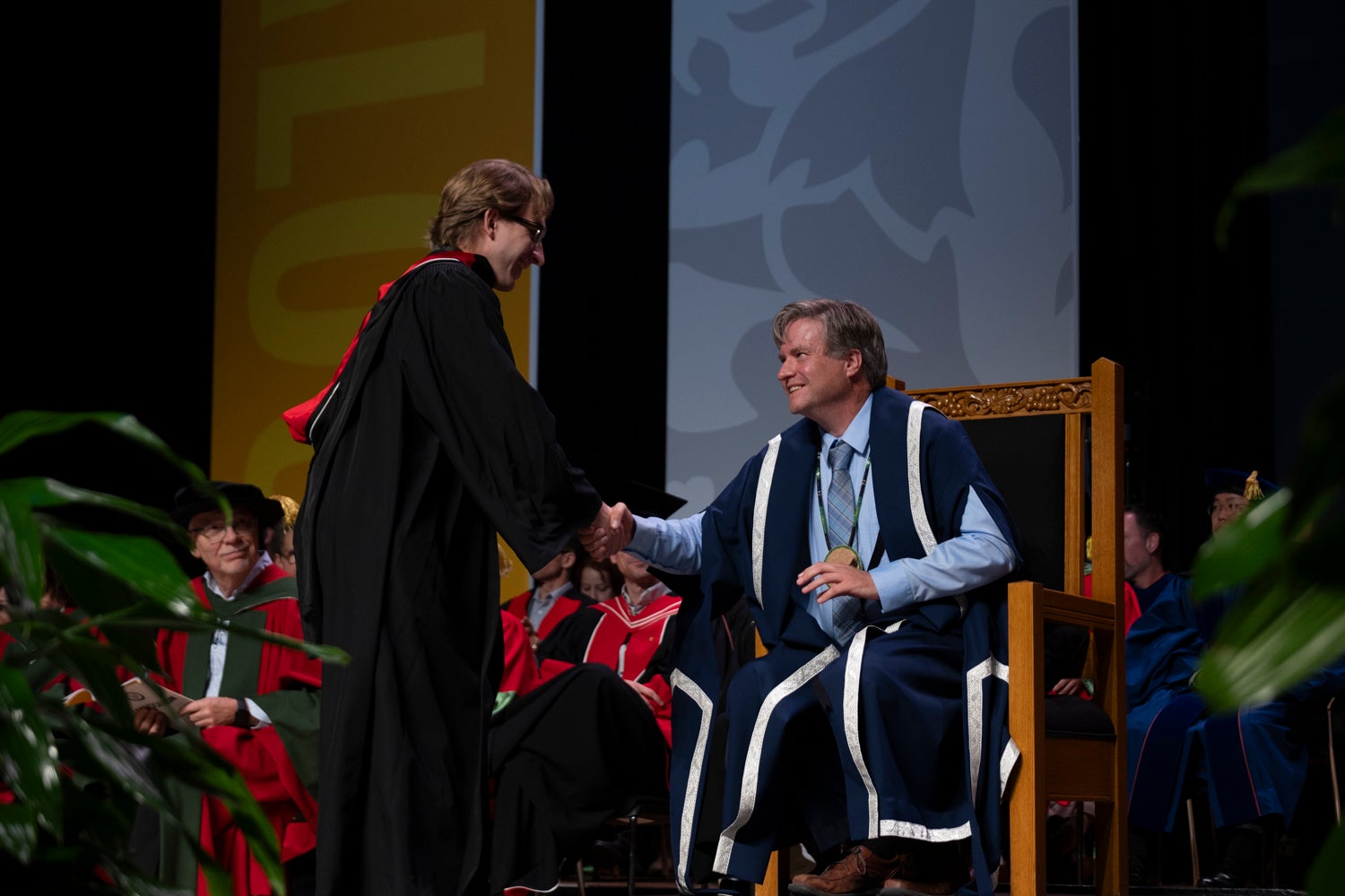 A graduate shakes the president's hand as he crosses the stage 