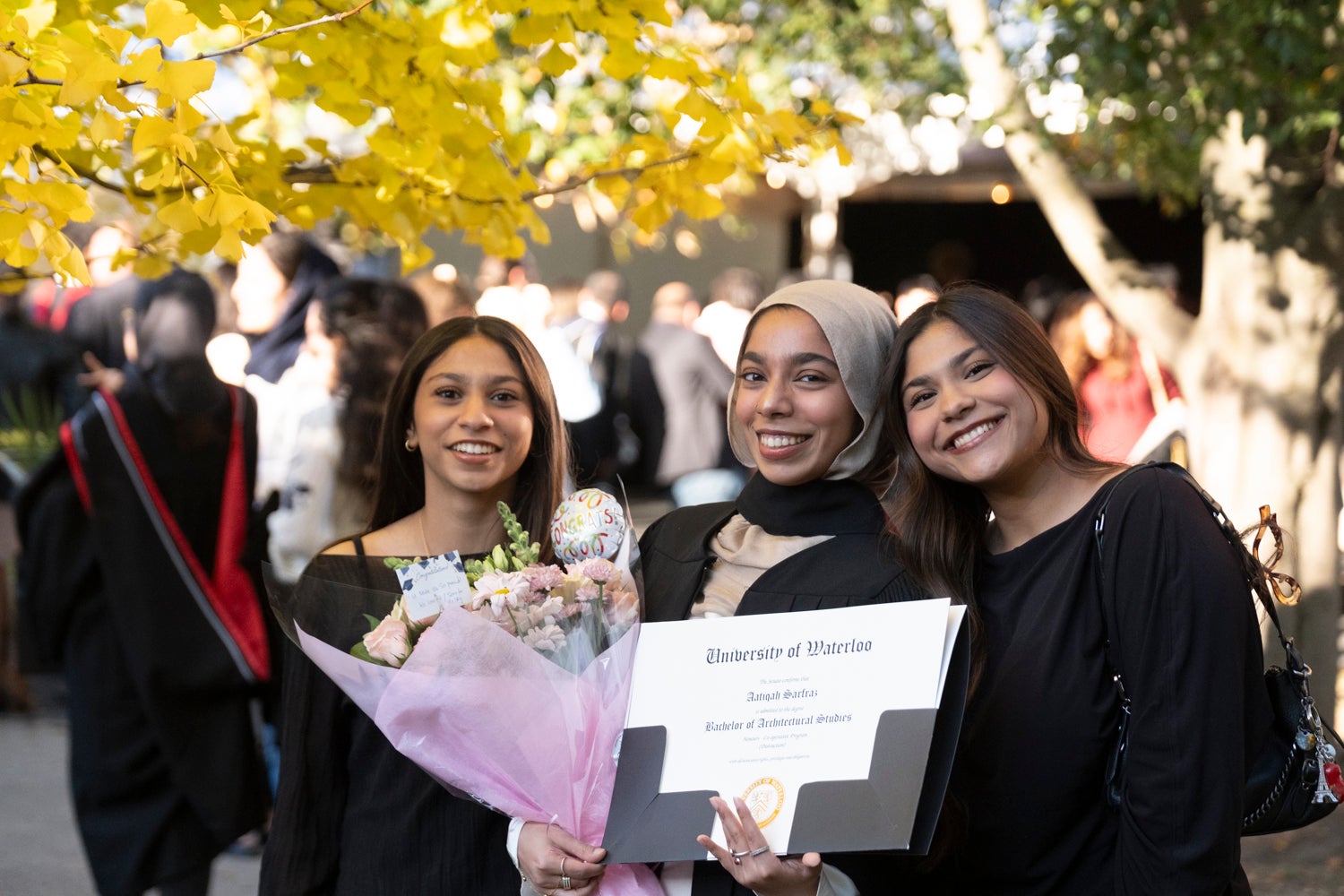 Three young woman pose outside with a Waterloo Engineering degree