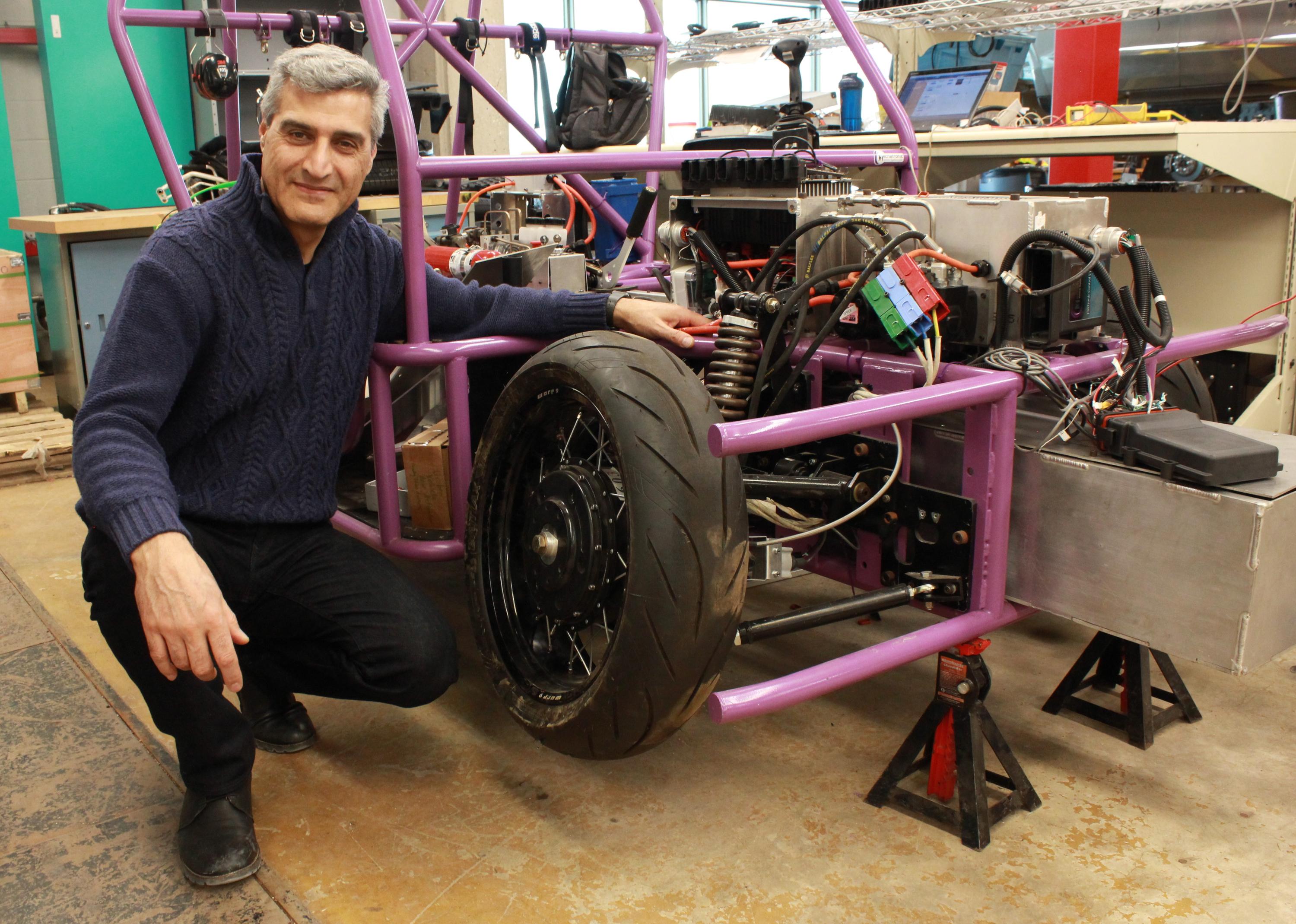 Amir Khajepour poses with a protype three-wheeled vehicle that uses new wheel units developed by Waterloo Engineering researchers.