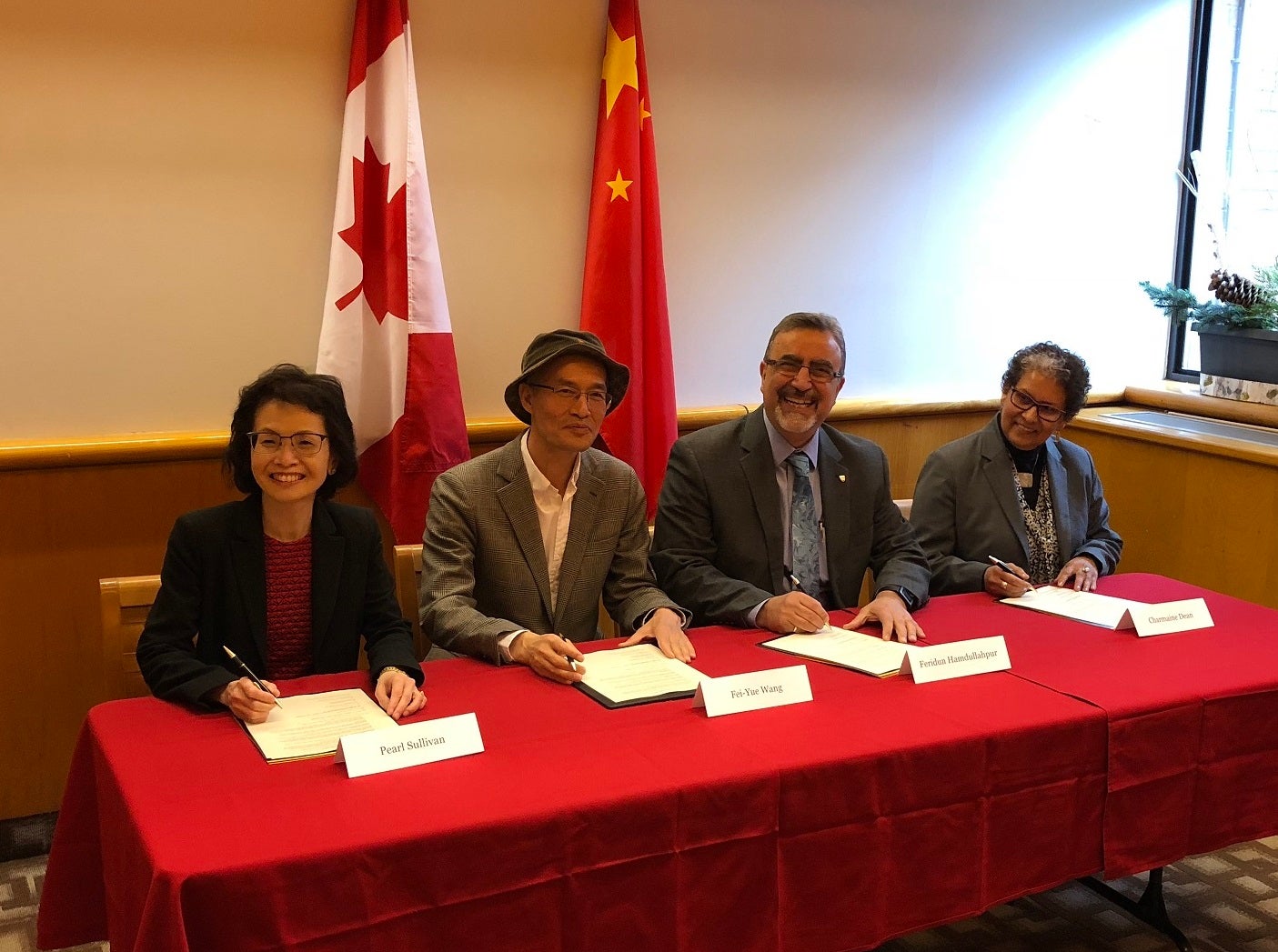 University of Waterloo officials Pearl Sullivan, Feridun Hamdullahpur and Charmaine Dean sign a research agreement with Fei-Yue Wang of the Qingdao Academy of Intelligent Industries (QAII) in China.