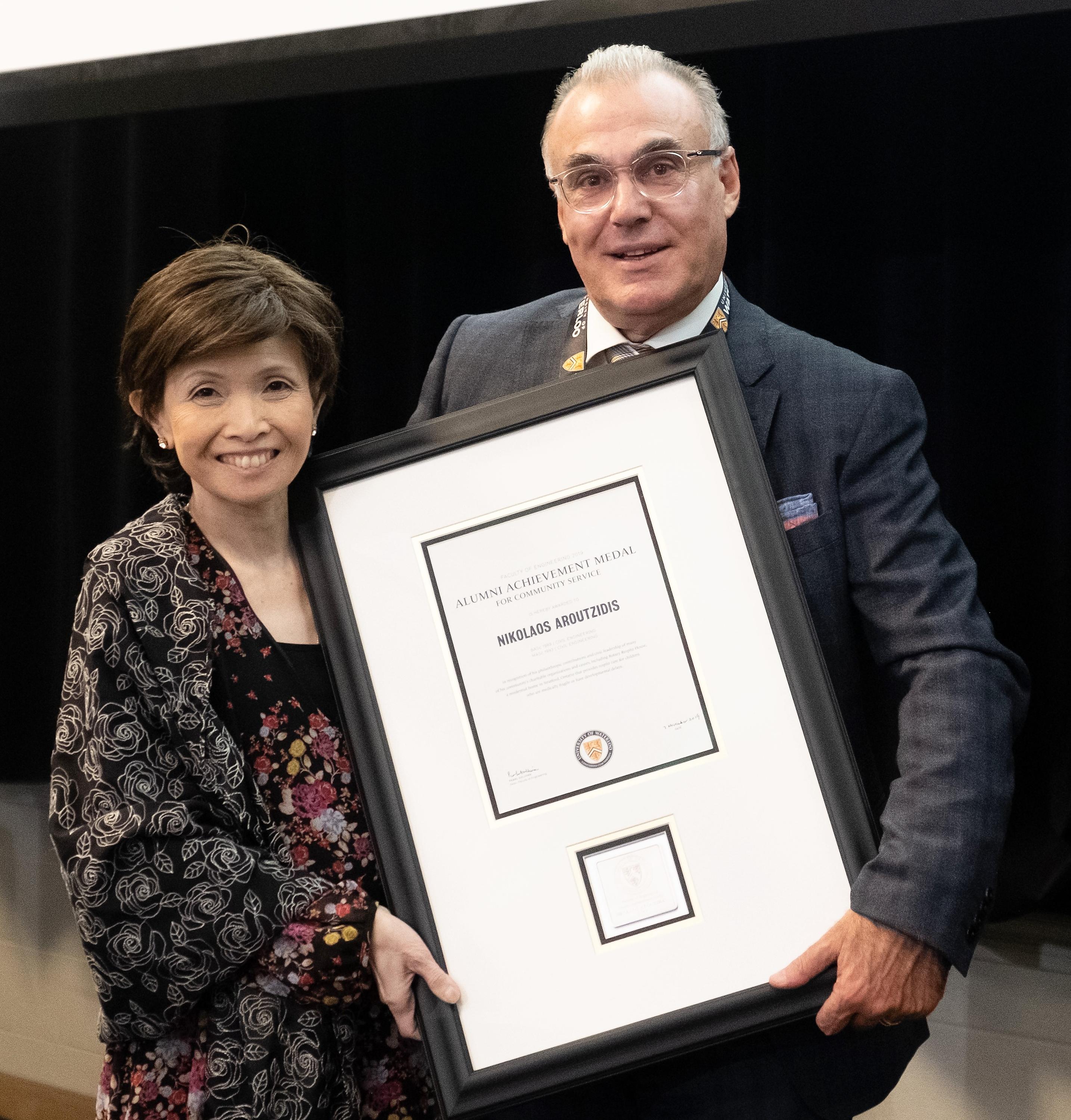 Dean Pearl Sullivan, left, presents the Alumni Achievement Medal in Community Service to Nick Aroutzidis.