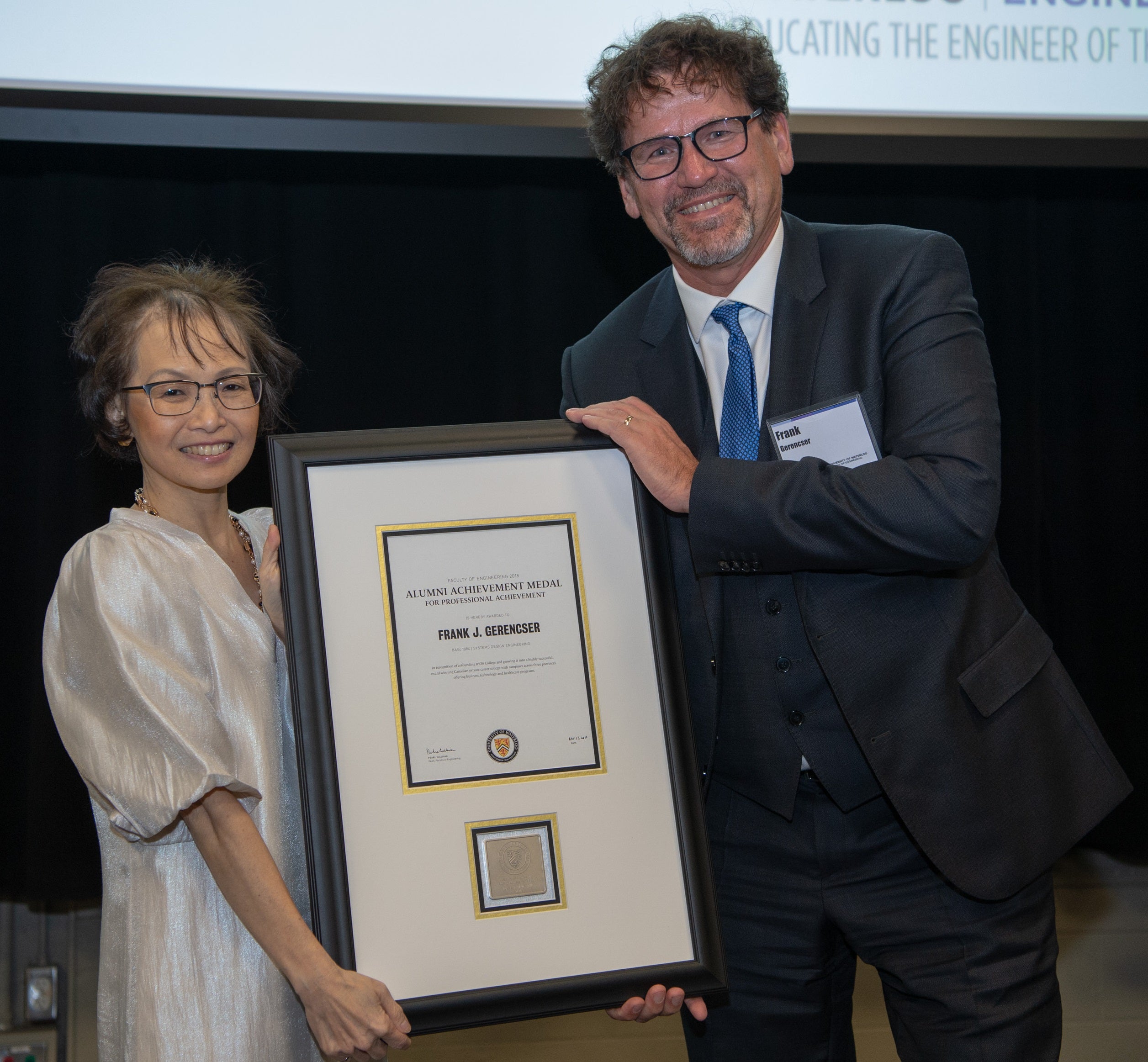 Frank Gerencser, co-founder of triOS College, receives his alumni award for professional achievement from Dean Pearl Sullivan.