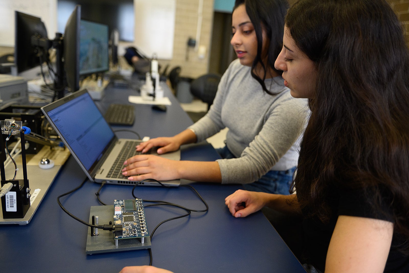 Students working on a laptop and hardware system