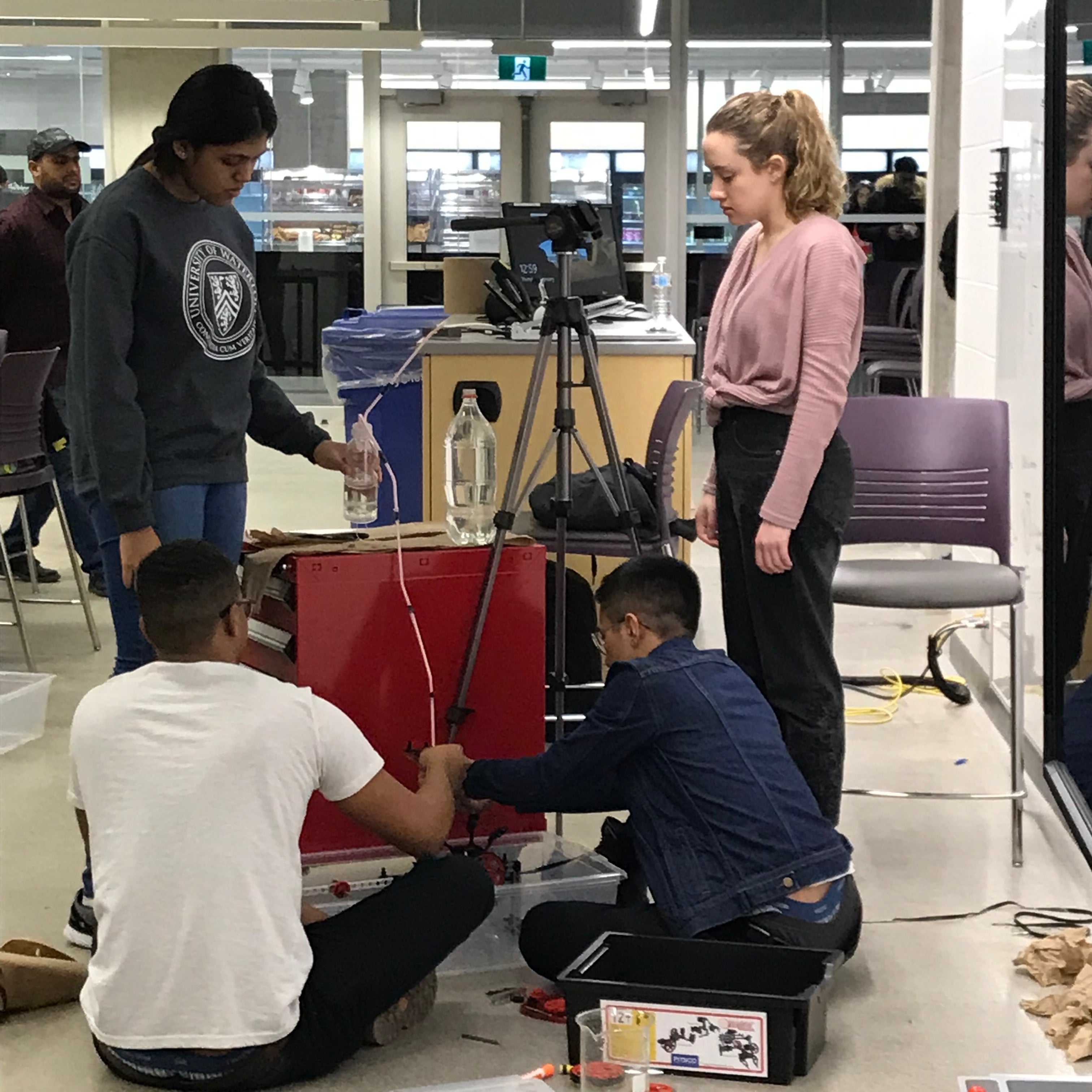 Students stand around their project, working on it together, in the IDEAs Clinic.