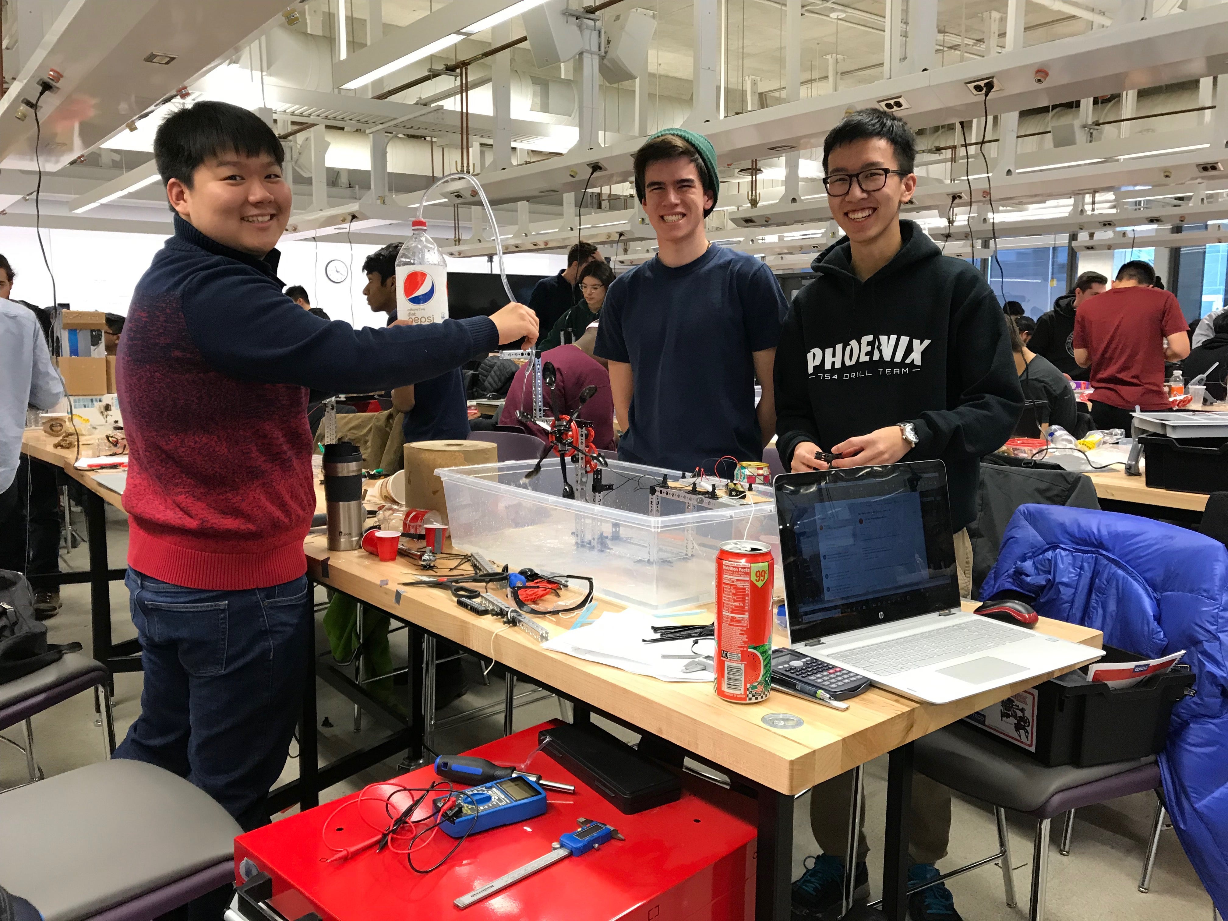 A group of young men working on a project, smiling at the camera