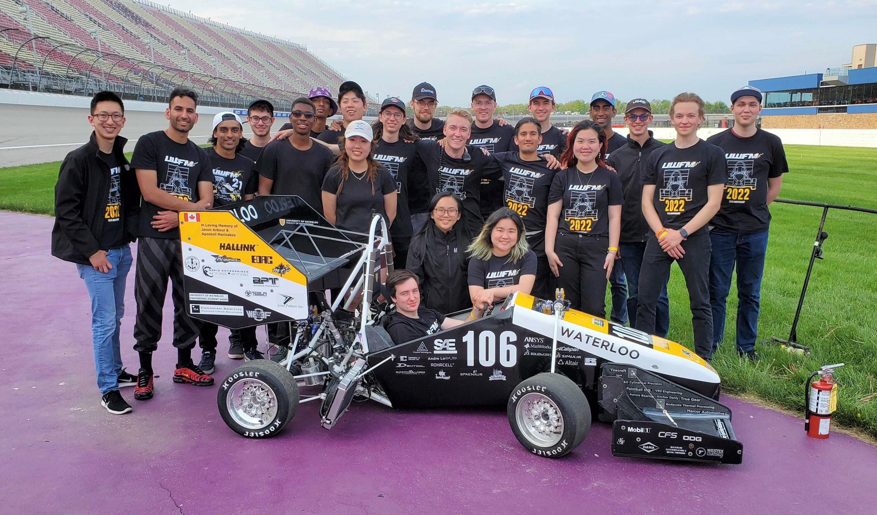 Members of UW Formula Motorsports pose with their car at the Michigan International Speedway.