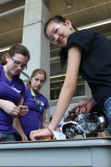 Girls taking apart an engine