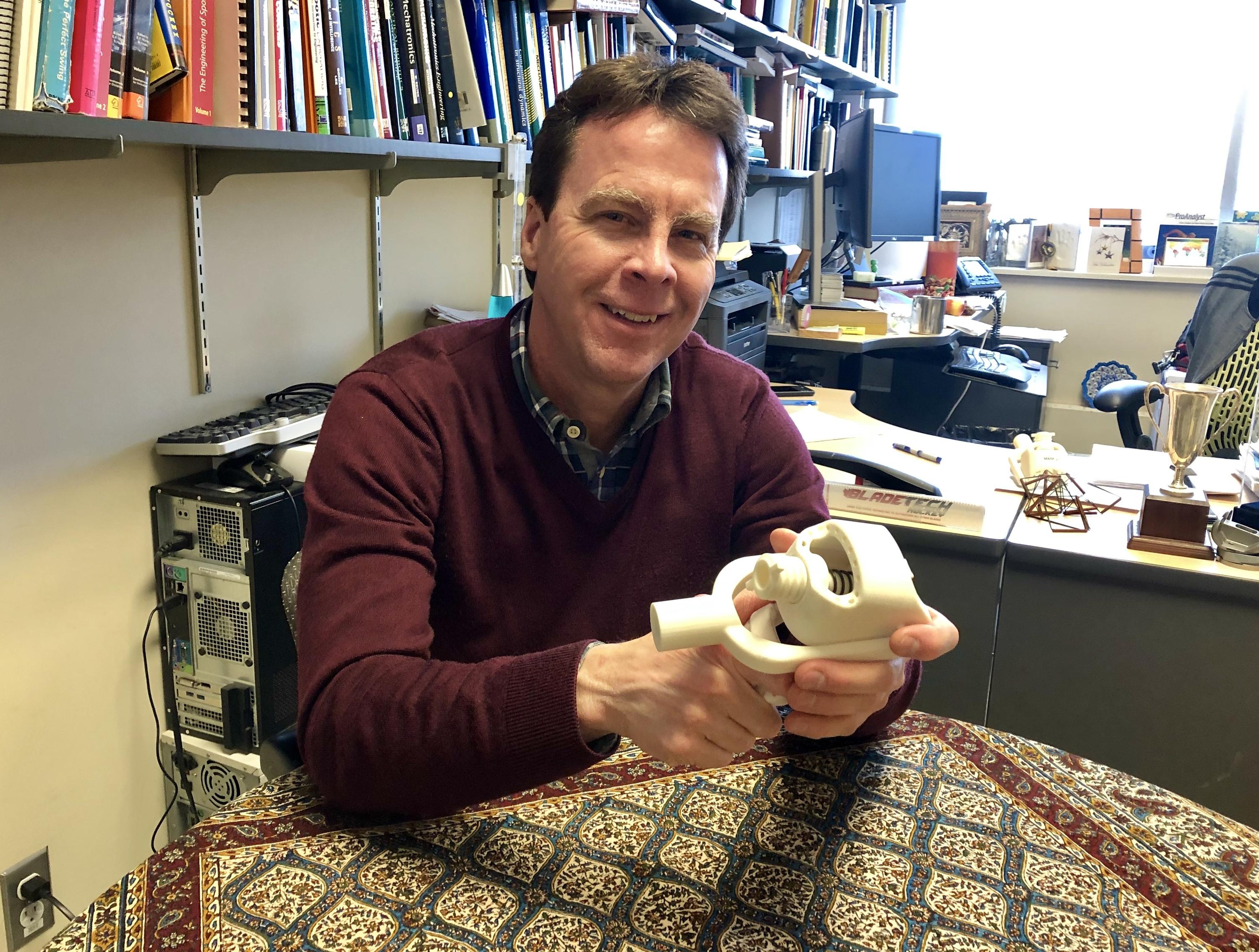 Engineering professor John McPhee displays the seventh prototype of a device designed to give wheelchair curlers better control of their shots.