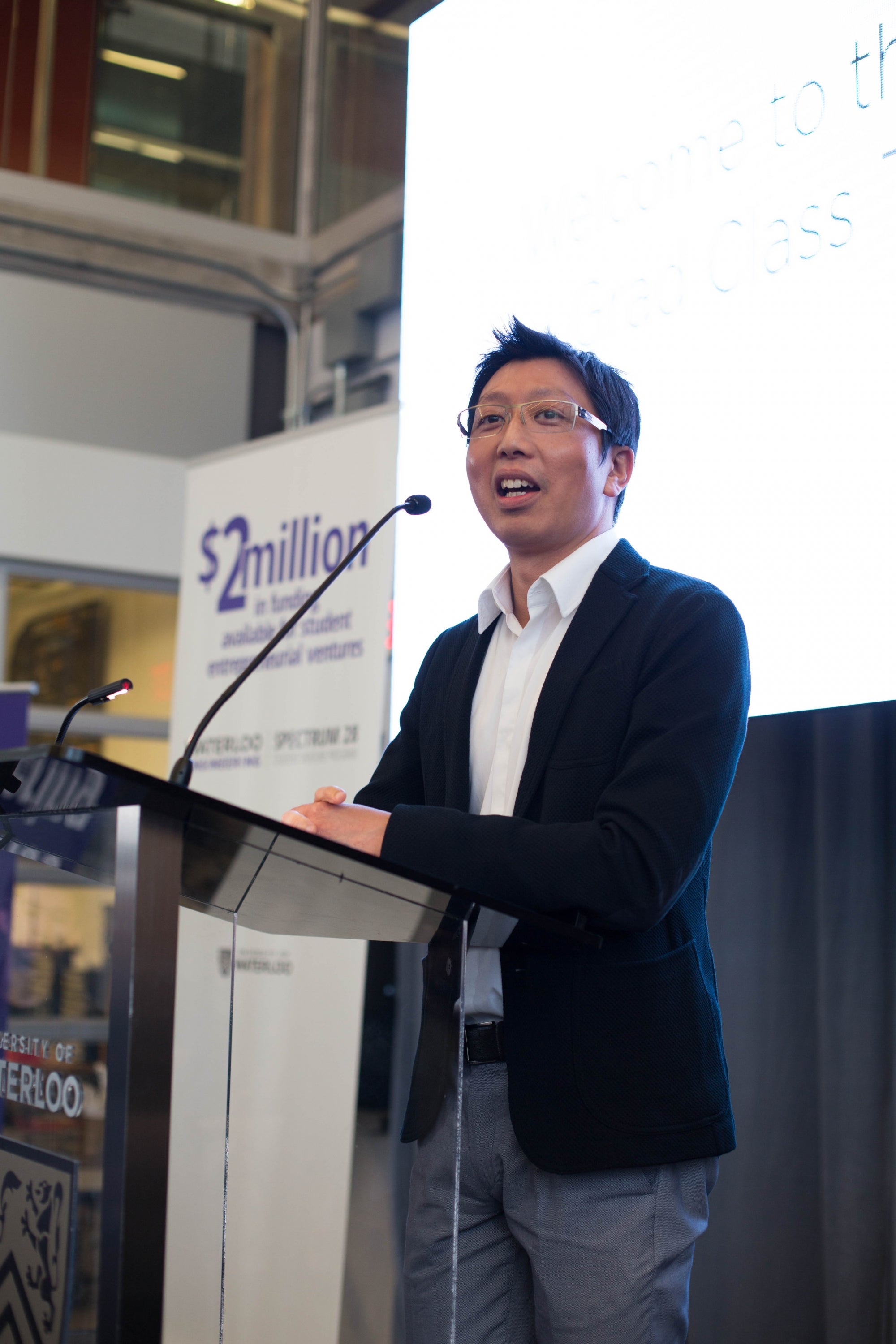 Lyon Wong standing on the podium, speaking at an event